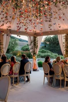 a group of people sitting around a table under a canopy covered in white drapes