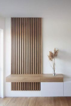 a room with wooden slats on the wall and a plant in front of it