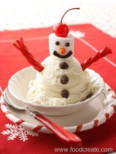 a small snowman sitting in a white bowl on top of a red table cloth