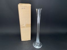 a clear vase sitting next to a cardboard box