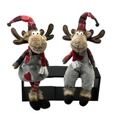 two stuffed reindeers sitting on top of a black bench with red and white striped hats