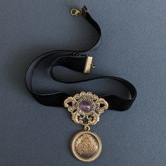 Witch Necklace with Gothic Pendant on Black Velvet Ribbon Choker Embrace your inner enchantress with this Witch Necklace, featuring a striking Gothic Pendant on a luxurious Black Velvet Ribbon Choker. Perfect for adding a touch of fantasy to your collection, this piece serves as Fantasy Jewelry for Renaissance Fair and Vintage Costume Jewelry for Women. The pendant, crafted from bronze and adorned with a captivating amethyst, showcases intricate gothic design elements. The rich black velvet ribb Gothic Costume Jewelry Choker, Elegant Costume Jewelry Choker, Victorian Metal Choker As Gift, Victorian Metal Choker For Gift, Victorian Metal Choker Gift, Victorian Style Adjustable Choker Jewelry, Vintage Purple Choker Necklace, Adjustable Victorian Style Choker Jewelry, Gothic Pendant Choker For Party