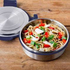 a blue and silver bowl filled with food on top of a wooden table