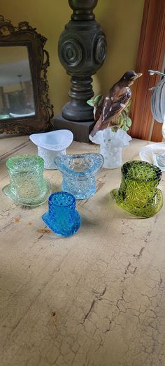 five glass bowls sitting on top of a wooden table next to a mirror and lamp