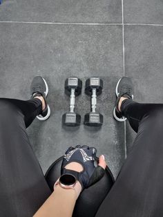 a person sitting on the ground with their legs crossed and two dumbbells in front of them