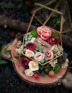 an arrangement of flowers and greenery is displayed on a piece of wood in the shape of a hexagonal box