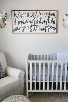 a baby's room with a white crib and deer head on the wall