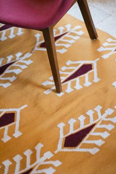 a red chair sitting on top of a wooden floor next to a yellow and white rug