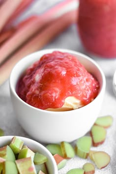 two bowls filled with food sitting on top of a table next to apples and cinnamon sticks