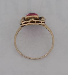 Ladies 10 karat synthetic ruby ring. The ring contains a rectangular ruby surrounded by a filigree shadow box with small gold ornamental knobs at the corners and at the center points of the milgrain edged box. The edwardian style antiqued ring is size 5.25. Victorian Ruby Ring In Yellow Gold With Intricate Design, Victorian Yellow Gold Ruby Ring With Intricate Design, Victorian Ruby Ring With Center Stone, Antique Ruby Signet Ring, Victorian Rings With Rose Cut Red Diamonds, Antique Red Signet Ring In 14k Gold, Antique Red 14k Gold Signet Ring, Victorian 14k Gold Ruby Ring With Intricate Design, Victorian Red Rings With Rose Cut Diamonds