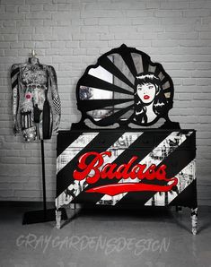 a black and white bed with red lettering on the headboard next to a mannequin