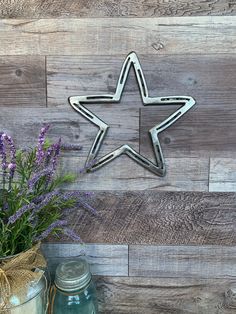 a metal star on the side of a wooden wall next to some lavenders and mason jars