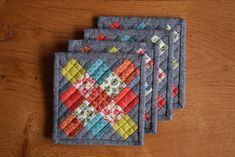 four quilted coasters on a wooden table