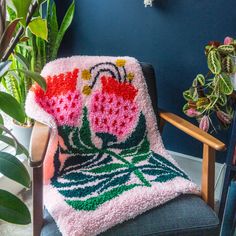 a crocheted blanket sitting on top of a chair next to a potted plant