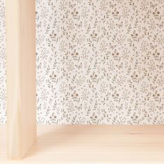 the corner of a room with a wallpapered pattern and wooden frame in front of it