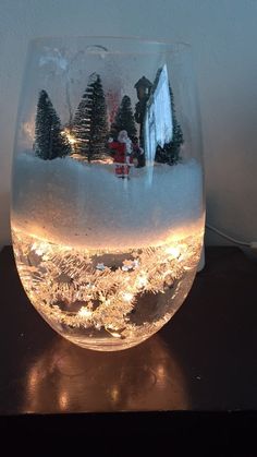 a wine glass filled with water and lit up christmas trees in the middle of it