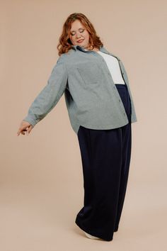 a woman is standing in front of a beige background and she has her arms outstretched