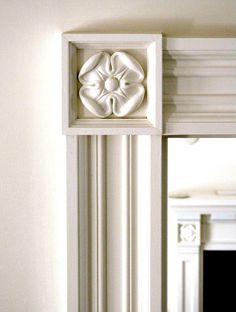 a white fireplace mantel with a decorative flower on it