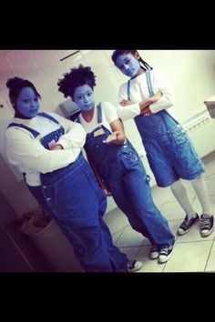 three people in overalls and blue paint on their faces are standing in front of a mirror