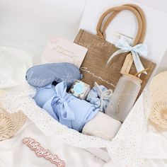 a basket filled with baby items sitting on top of a white bed next to a bag