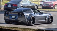 a silver sports car parked in a parking lot next to other cars on the street