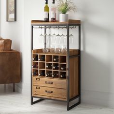 a wooden cabinet with wine glasses and bottles on it next to a couch in a living room