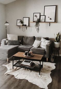 a living room with gray couches and pictures on the wall above it's coffee table