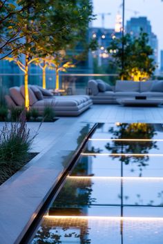 an outdoor living area with couches, tables and water feature in the foreground