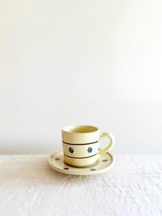 a cup and saucer sitting on top of a white tablecloth covered table cloth