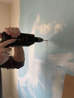 a man using a drill to paint a wall