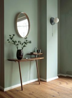 a wooden table with a mirror and vase on it