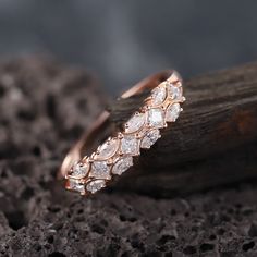 two wedding rings sitting on top of a piece of wood next to some rocks and dirt