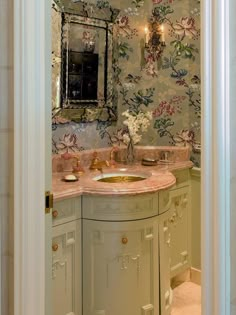 a bathroom sink sitting under a mirror next to a wall mounted faucet with flowers on it