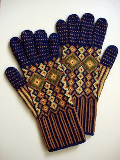 a pair of blue and gold gloves sitting on top of a white table next to each other