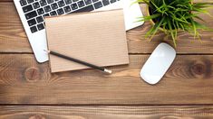 an open laptop computer sitting on top of a wooden desk next to a mouse and keyboard