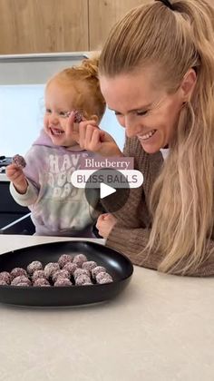 a woman holding a baby and looking at some food