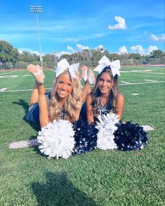 two cheerleaders laying on the ground with their pom poms in hand