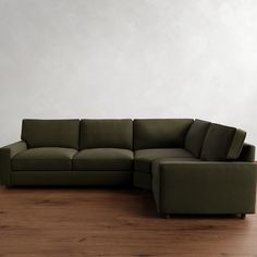 a large green couch sitting on top of a wooden floor next to a white wall