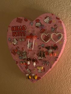 a pink heart shaped wall hanging with hello kitty on it's side and other decorations