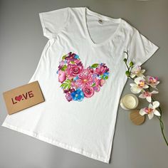 Experience the charm of nature with this hand-painted T-shirt, showcasing a beautiful heart-shaped arrangement of delicate flowers. Each T-shirt is a unique piece of wearable art, thoughtfully designed for women who value originality and elegance. Crafted with care, this shirt makes a meaningful and stylish gift for her, perfect for any occasion. Size S T Shirt Painting, Trendy Shirt Designs, Painted Clothes, Unique Gifts For Her, How To Make Tshirts, Stylish Gifts, Wearable Art, Womens Clothing Tops, Unique Pieces