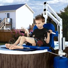 a young boy sitting on top of a blue chair next to a pool with a ladder