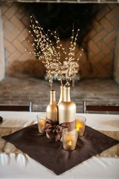 three vases with candles are sitting on a table in front of a fire place