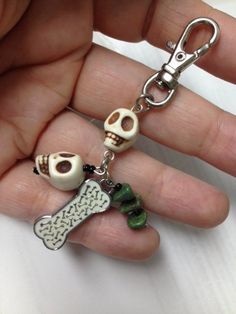 a hand holding a key chain with two skulls and a skull on it's side