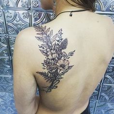 a woman's back tattoo with flowers on it