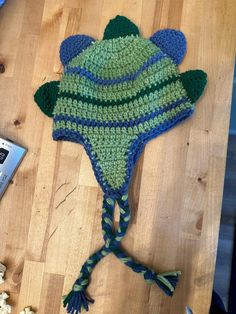 a crocheted frog hat sitting on top of a wooden table