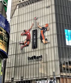 an advertisement on the side of a building in tokyo, japan with two basketball players jumping up and down