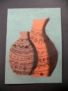 an orange and black vase sitting next to each other on a piece of blue paper