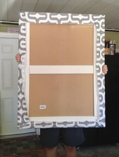 a person holding up a large cardboard box with white tape on it's sides