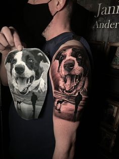 a man with a tattoo on his arm holding up a dog's face next to a mirror