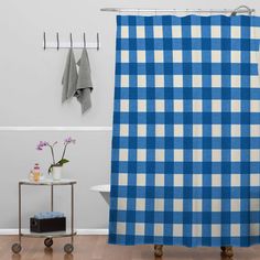 a blue and white checkered shower curtain next to a shelf with towels on it